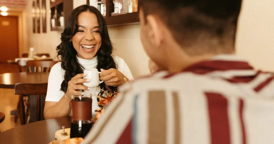 Pareja platicando y riendo durante una cita en una cafetería