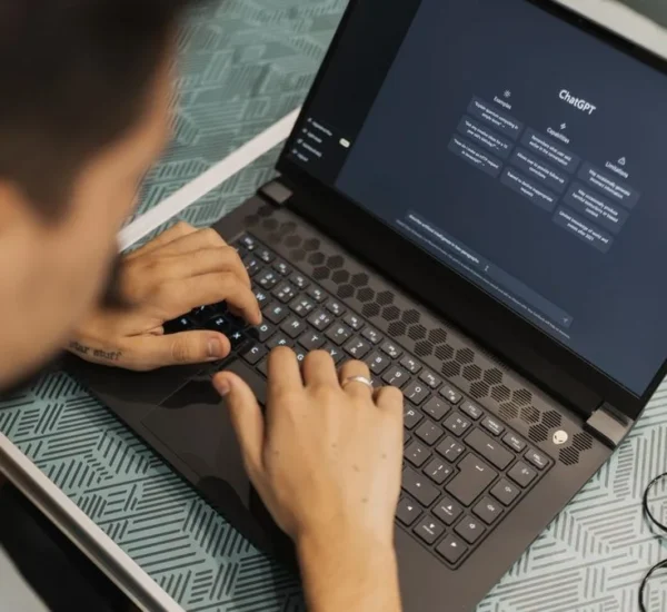 Persona escribiendo una pregunta a un asistente de inteligencia artificial en su laptop