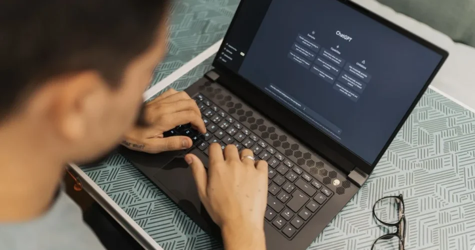 Persona escribiendo una pregunta a un asistente de inteligencia artificial en su laptop
